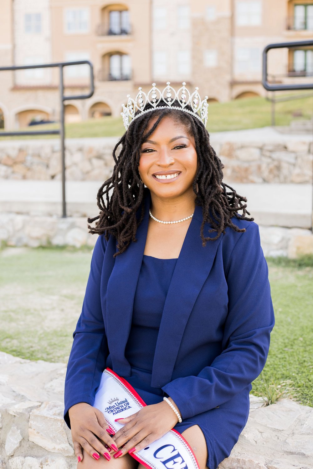 Dr. Christiana Redeaux seated, wearing her Ms. Central South crown and sash